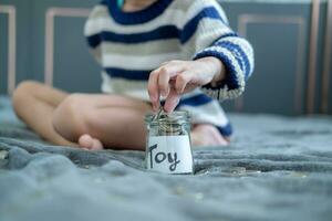 Asian boy sits and puts coins in a glass jar to save money to buy toys. photo