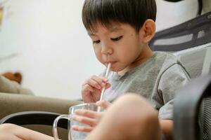 asiático chico es Bebiendo un vaso de Leche foto