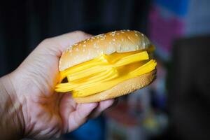 A man's hand holds a large amount of hamburger and cheese slices. photo