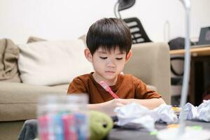 Asian boy drawing on table And there was a piece of paper left on the table. photo