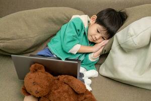 Asian boy sleeping while studying online on laptop photo