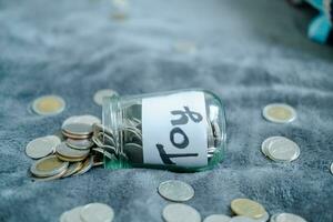 A glass bottle with the word toy on it. and silver coins for savings The glass is full until the glass falls. photo