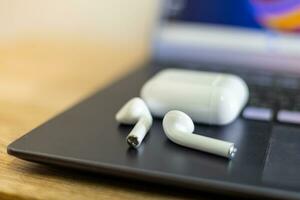 White wireless headphones on the computer, blurry background photo