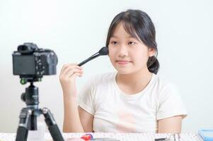 Beauty girl blogger concept, Asian woman use makeup brush and review in live streaming isolated photo