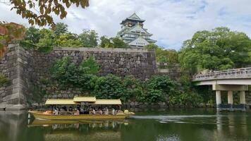 osaka, Giappone su 3 ottobre 2023. metraggio di osaka castello su un' soleggiato estate giorno, con un' turista barca su il fiume in giro esso. video