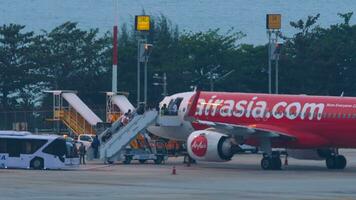 phuket, Tailandia febrero 27, 2023 - embarque pasajeros en el avión airasia. personas con equipaje Vamos arriba el escalera a el aeronave. pasajero avión. viaje concepto. moderno internacional aeropuerto video