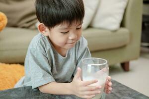 asiático chico es Bebiendo un vaso de Leche foto