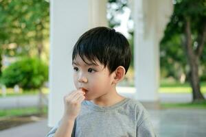 The face of an Asian boy standing and eating ice cream. photo