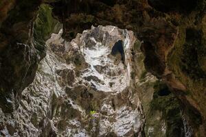 Low angle view of a dark cave exit with sunlight streaming into the cave shaft. photo