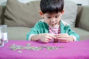 Young Asian boy counting coins for saving money photo