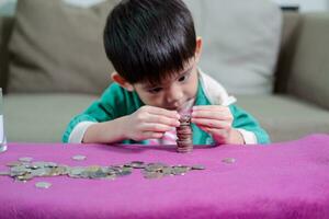 Young Asian boy counting coins for saving money photo