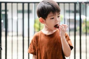 Happy face of Asian boy eating chocolate candy photo