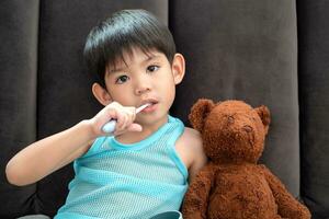 Asian boy brushing his teeth on the living room photo