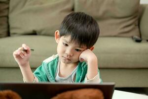 Asian boy studying online and doing activities on laptop photo