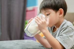 asiático chico es Bebiendo un vaso de Leche foto