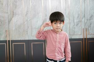 Asian boy stands with his hand pointing at his head. Pretending to be thinking about something photo