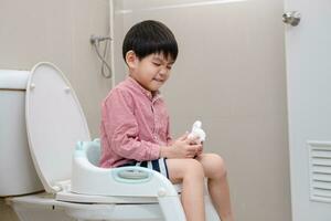 Asian boy Sitting on the toilet bowl in hand holding tissue photo