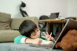 Asian boy studying online and doing activities on laptop photo