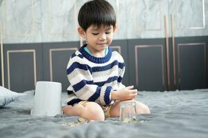 Asian boy happily counting coins to save money photo