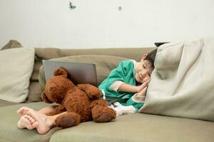 Asian boy sleeping while studying online on laptop photo