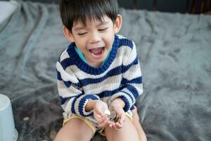 Asian boy happily counting coins to save money photo