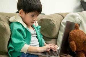 Asian boy studying online and doing activities on laptop photo