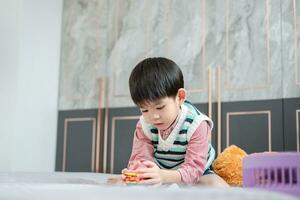 asiático chico jugando con rompecabezas rompecabezas en el cama alegremente foto
