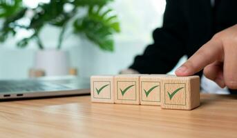 Businessman hand pushes the correct green symbol on a wooden cube for a business proposal and concept approval document. photo