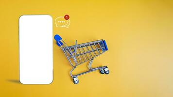 Shopping car and empty smartphone on yellow background. shopping online concept. photo