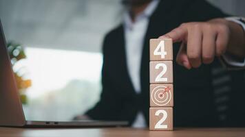 Wooden blocks lined with 2024 letters with dart board and businessman expressing goal setting and startup concept. photo