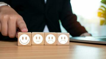 Businessman pointing fingers at smiley face and sad face on wooden block for positive thinking selection concept. Concepts of mental health and emotional state. photo