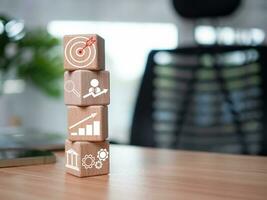 Wooden blocks and business icons on table wood represent the concept of business strategy and setting business goals. photo