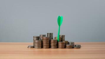 The green arrow hits the target in the center of a row of coins on the wooden floor. Concepts of finance, savings and investment. Business growth concept, finance goals concept. photo