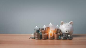 Piggy bank and coins lined up on wooden floor with candlesticks and arrows on a white background. Concepts of finance, savings and investment. photo