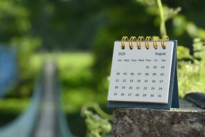 August 2024 calendar with green blurred background of hanging bridge. photo