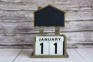 Chalkboard with January 11 date on white cube block on wooden table. photo