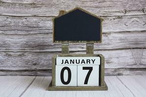 Chalkboard with January 07 date on white cube block on wooden table. photo