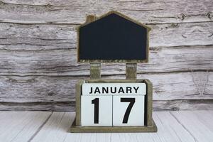 Chalkboard with January 17 date on white cube block on wooden table. photo