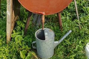 Rain barrel and watering can in vegetable garden photo