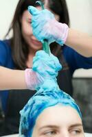 Hairstylist washes female head with dark blue hair color after hair dyeing process in beauty salon photo