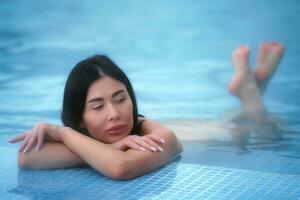 Brunette lies in thermal water in pool at spa and relaxes photo