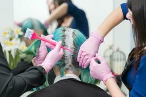 proceso de pelo tintura en belleza salón. dos peluquería aplicando pintar a pelo durante blanqueamiento pelo raíces foto