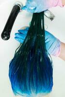 High-angle shot of hairdresser washes client's head with long hair sapphire color after hair dyeing process photo