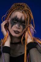 Fine art portrait of woman with orange color dreadlocks hairstyle and horror black stage make up photo