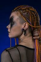 Headshot of young woman with horror stage make up painted on face and orange dreadlocks hairstyle photo