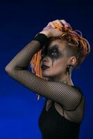 Young female with orange color braids hairdo and horror black stage makeup painted on face photo