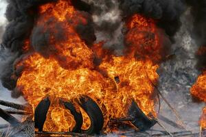 Burning automobile tires, strong flame of red fire, clouds of black smoke in sky photo