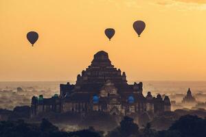 The beautiful scenery view of hot air balloons flying over Dhammayangyi temple the largest pagoda in Bagan during the sunrise in Myanmar. photo