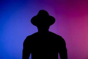 Silhouette head of sad african american man in hat on colourful neon isolated background - incognito concept photo