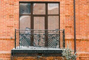 Facade of old house with beautiful balcony with snow in winter. Balcony with metal railings. photo